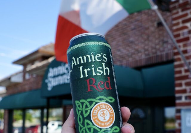 Holding up a beer can in front of Annie Gunn's restaurant entrance.